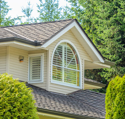 Close-up view of a residential shingled roof with large bay window on second story