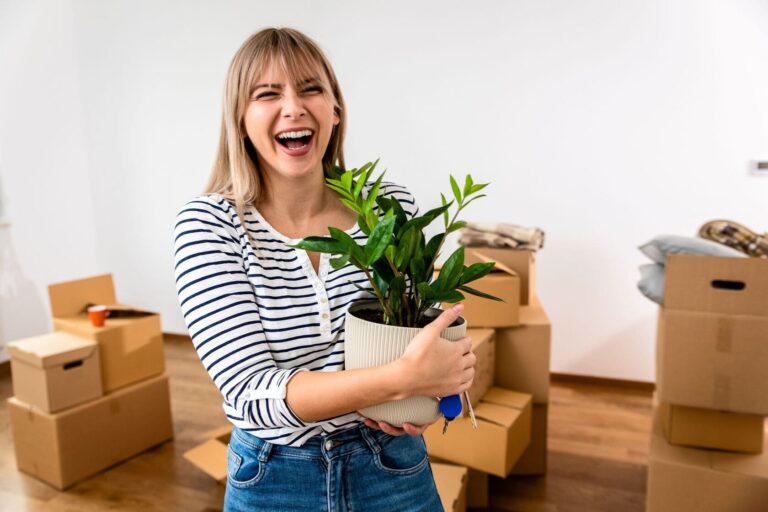 happy-woman-holding-potted-plant-after-moving