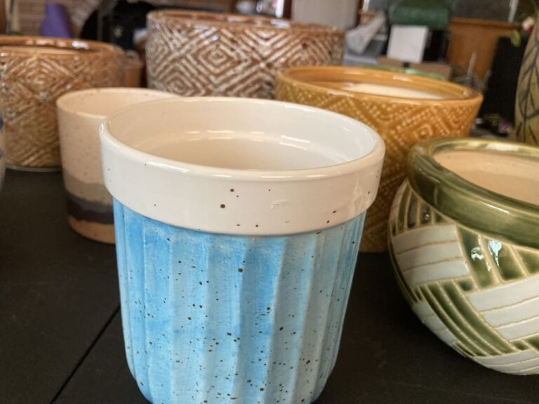 Assorted ceramic pottery, including blue pot with white rim in foreground