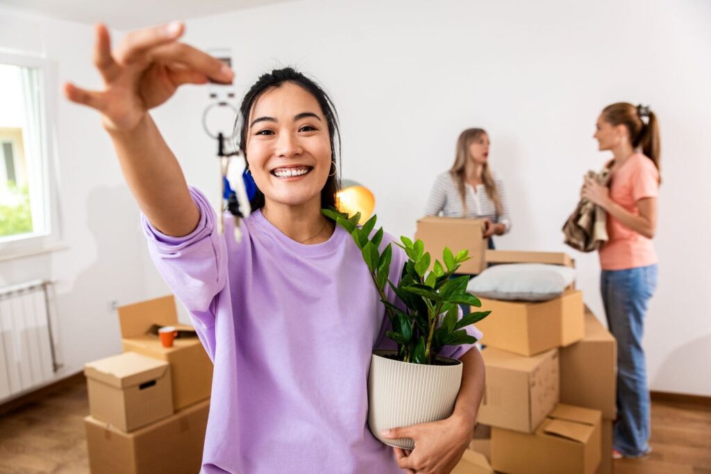 Happy woman holding a ZZ plant and keys to her new apartment