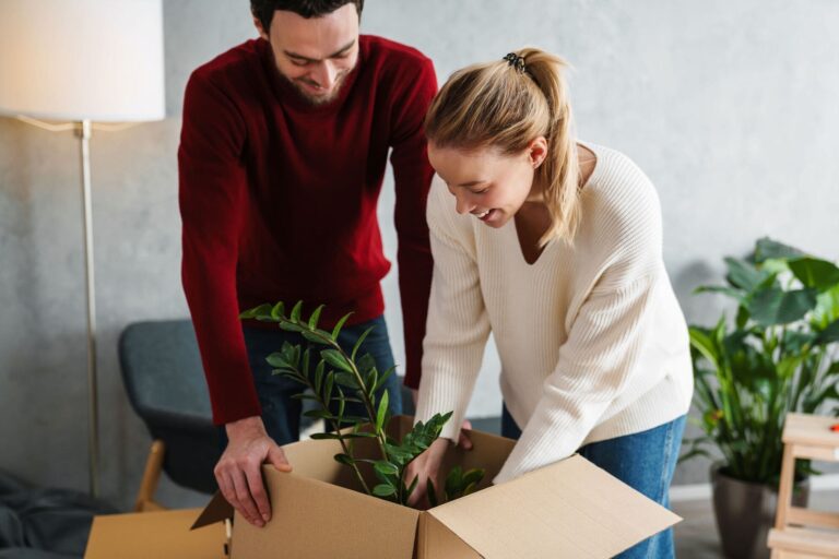 Happy couple packing a ZZ plant on moving day