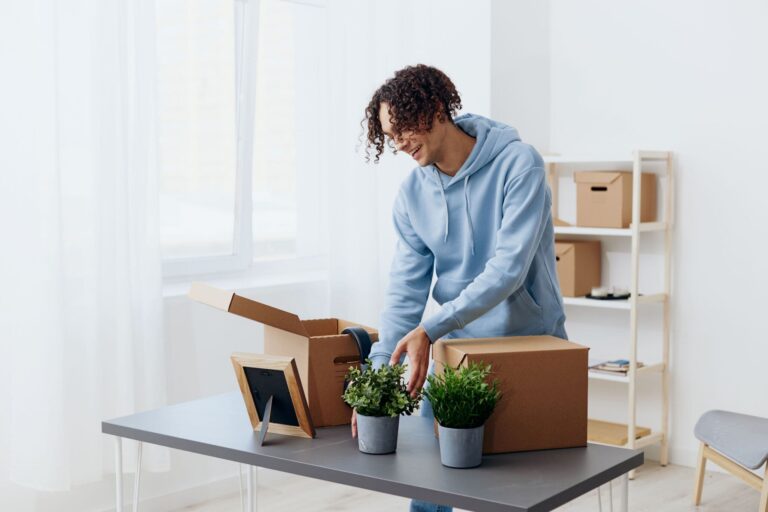 Happy man unpacking his houseplants and placing them on his desk